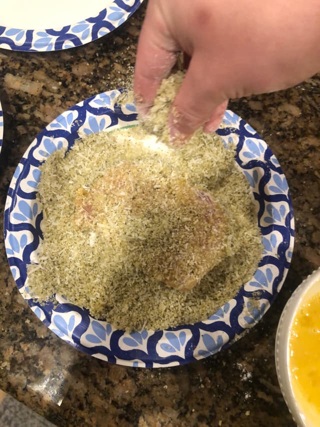 Putting breadcrumbs on the chicken